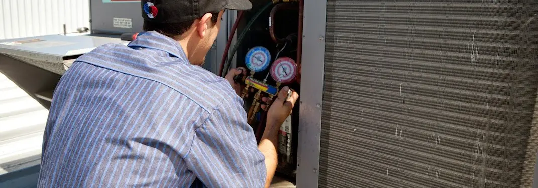 HVAC technician servicing a condenser unit in Leicester