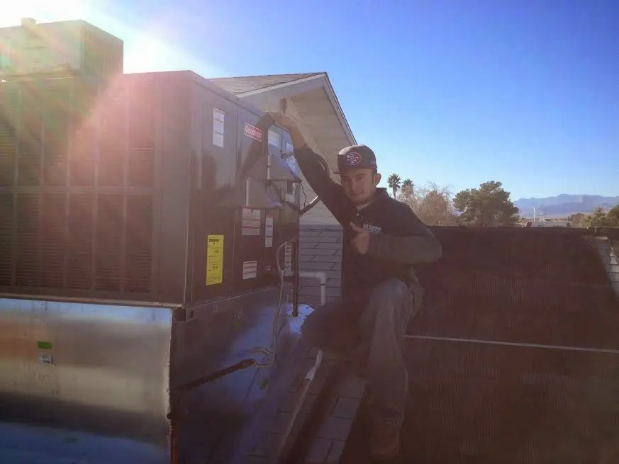 HVAC technician performing Air Duct Cleaning on a rooftop unit in Leicester